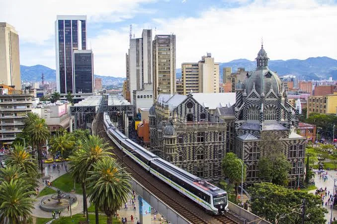 Vista panoramica del centro di Medellín, con la metropolitana sopraelevata, l'architettura storica della città, edifici moderni e le montagne delle Ande sullo sfondo.